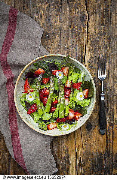 Close-up of salad with green asparagus  strawberries and daisies