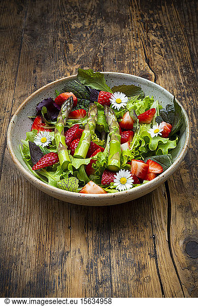 Close-up of salad with green asparagus  strawberries and daisies