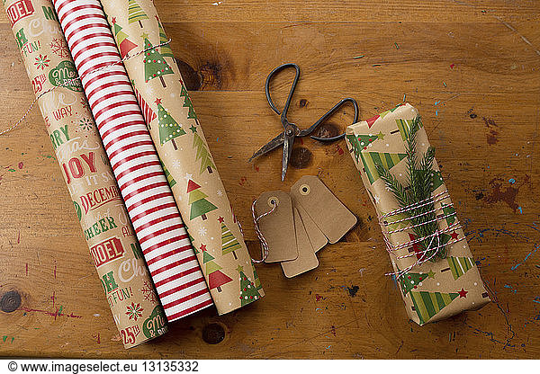 Close-up of scissors by rolled up wrapping papers and Christmas present on table