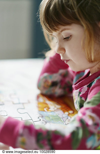 Close up of serious girl assembling jigsaw puzzle