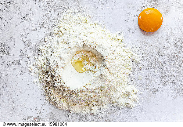 Close-up of single egg yolk and pile of flour