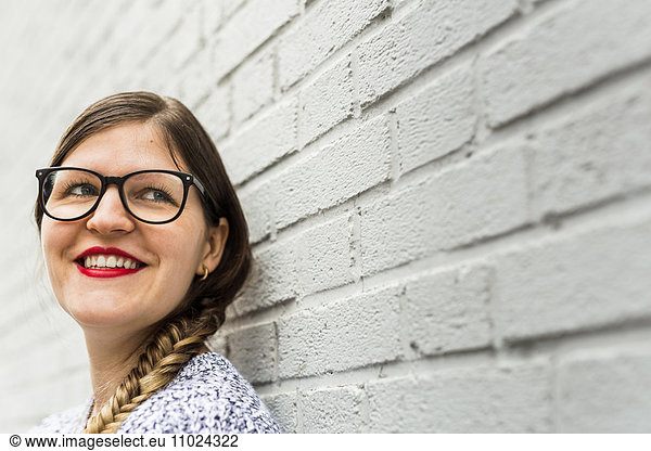 Close-up of smiling beautiful woman standing against wall