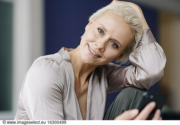 Close-up of smiling businesswoman using smart phone while sitting in office
