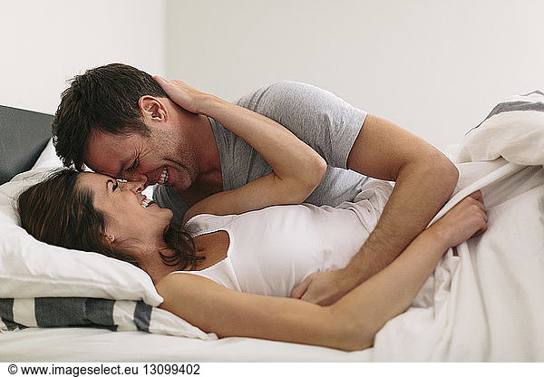 Close-up of smiling couple in bed at home