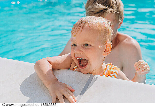 Close-up of smiling father and daughter by the side of the open pool