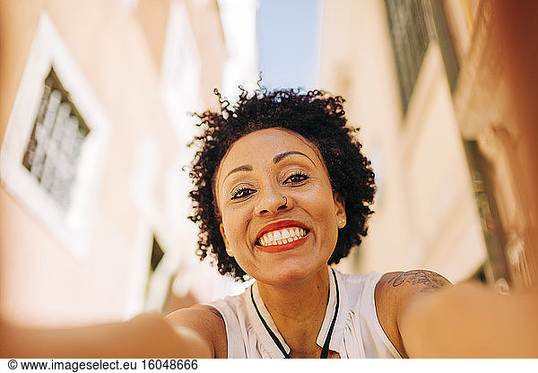 Close-up of smiling mid adult woman with curly hair against buildings in city