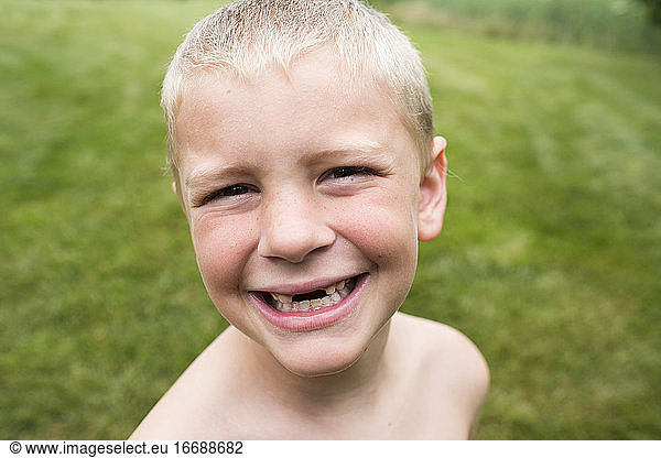 Close Up of Smiling Toothless Young Boy With a Buzz Cut in Backyard