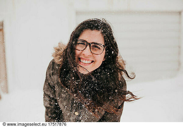 Close up of smiling woman with blowing hair during snow storm