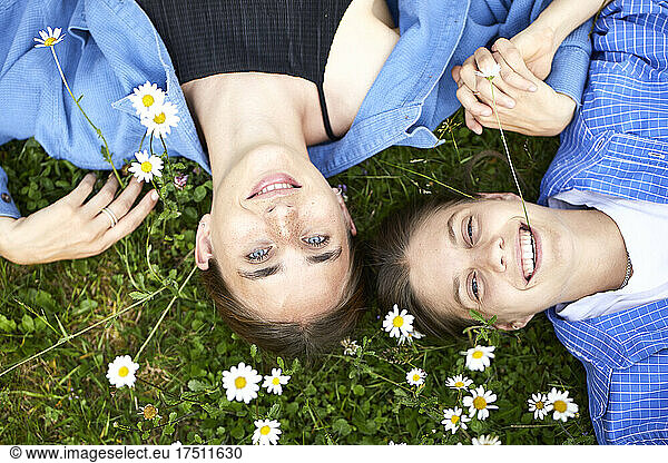 Close-up of smiling young friends lying on grassy land in garden