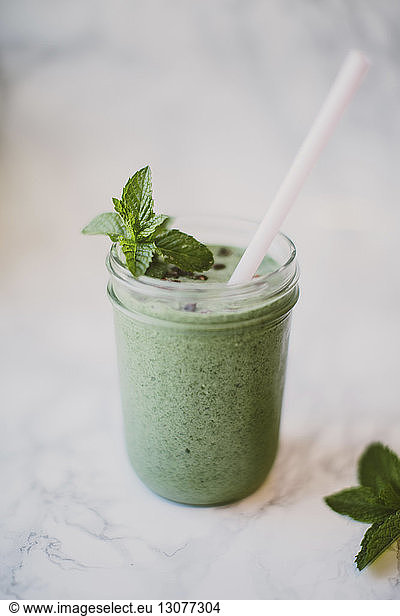 Close-up of smoothie with mint leaves and cacao nibs in mason jar on table