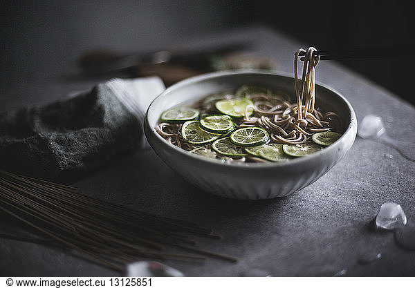 Close-up of soba noodles in bowl with chopsticks on kitchen counter