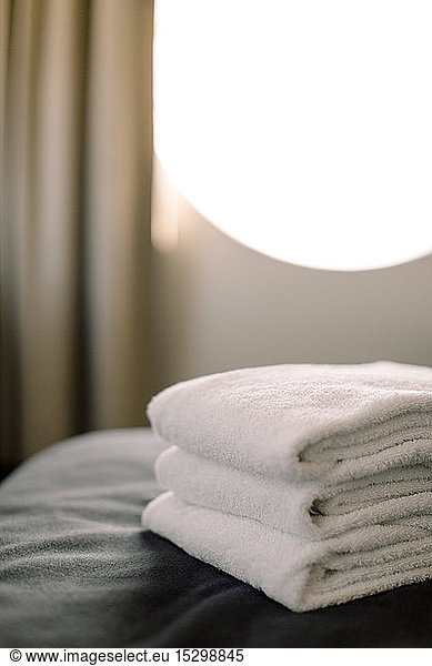 Close-up of stacked towels on bed in hotel