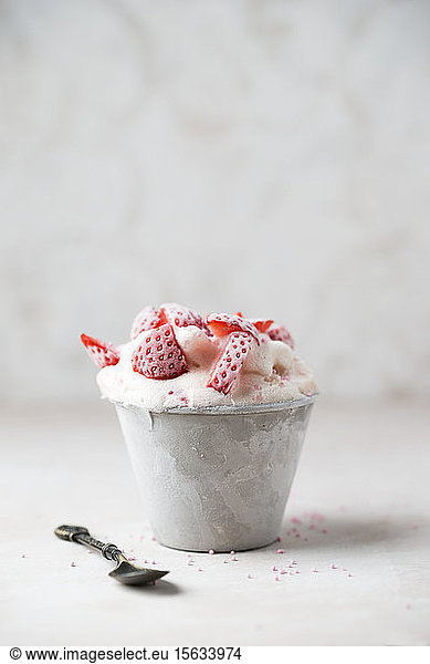 Close-up of strawberry ice cream served in bowl with spoon on table