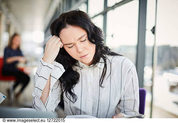 Close-up of stressed female student studying in university cafeteria