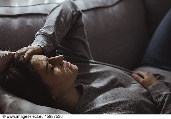 Close-up of stressed woman lying on sofa at home
