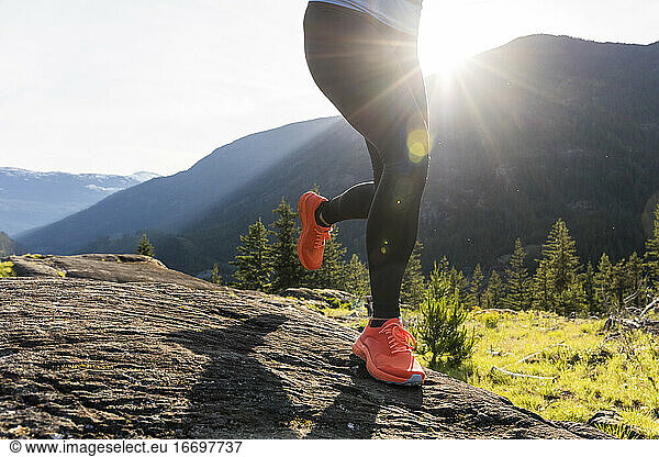Close up of strong sportswoman’s shoes while on a rocky mountain trail