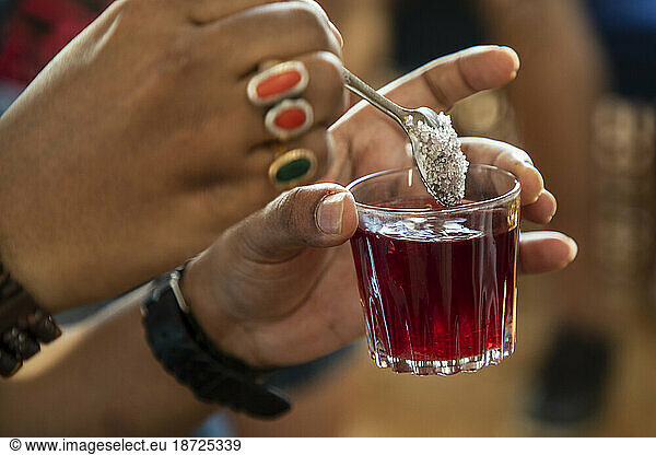 Close up of sugar being added to a glass of hibiscus tea in Egypt