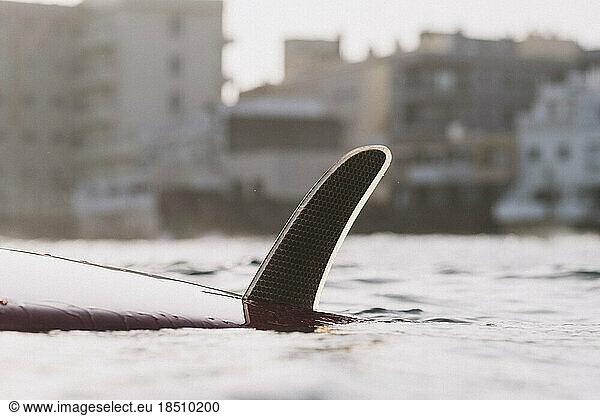Close up of surfboard and fin against buildings background