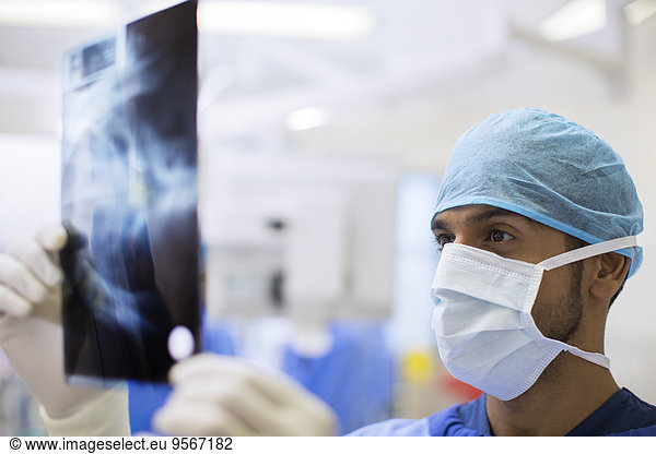 Close up of surgeon wearing surgical cap and mask looking at x-ray in operating theater