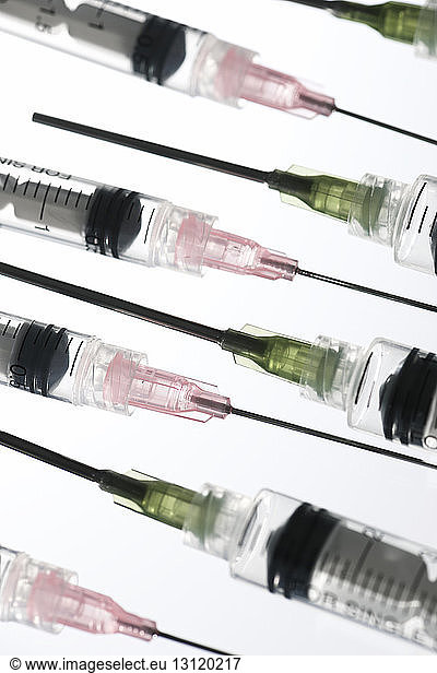 Close-up of syringes arranged on white background
