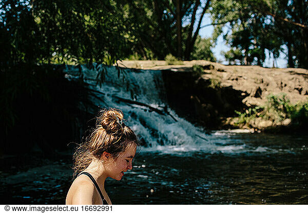 Close up of teen girl walking standing near a small waterfall