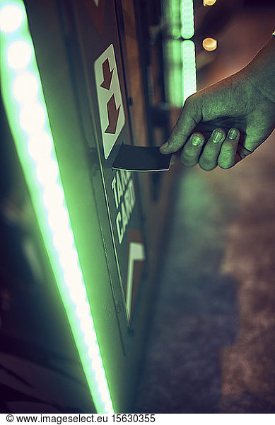 Close-up of teenage boy inserting card into machine in an amusement arcade