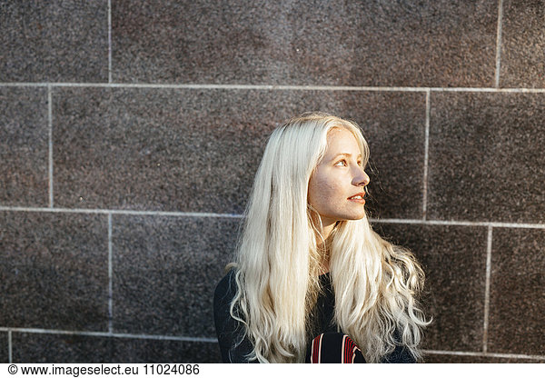 Close-up of teenage girl looking away against wall