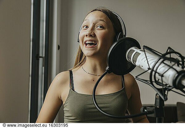 Close-up of teenage girl singing over microphone in studio