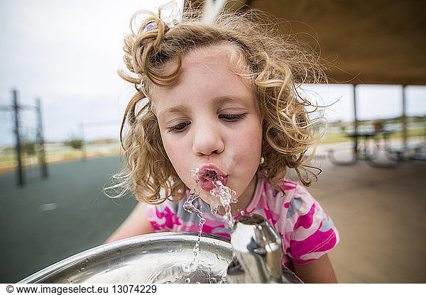 Close-up of thirsty girl drinking water