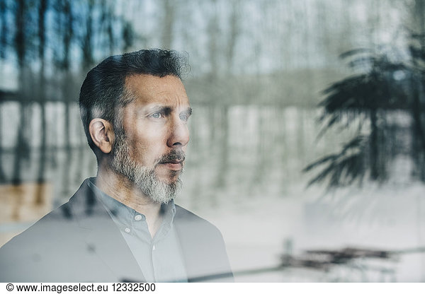 Close-up of thoughtful businessman seen through glass window at office