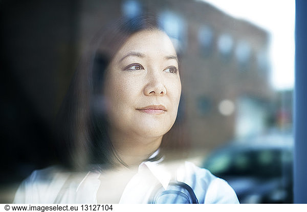 Close-up of thoughtful female doctor seen through window