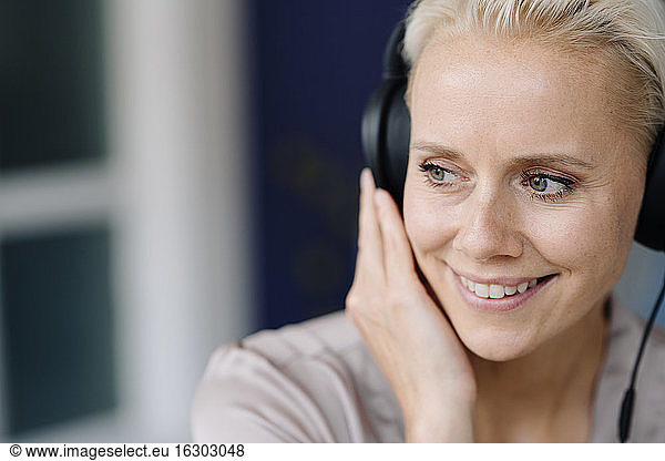 Close-up of thoughtful female entrepreneur listening music over headphones looking away in office