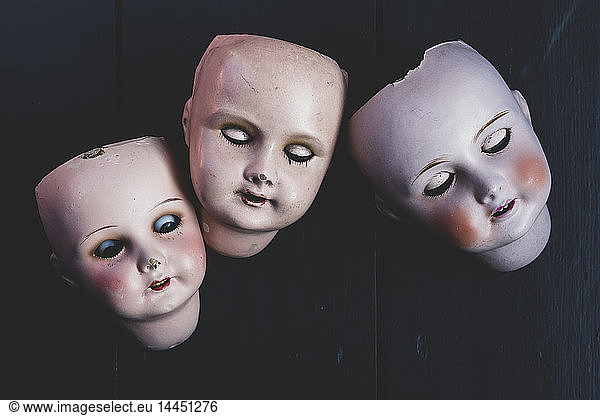 Close up of three porcelain dolls' heads on black background.