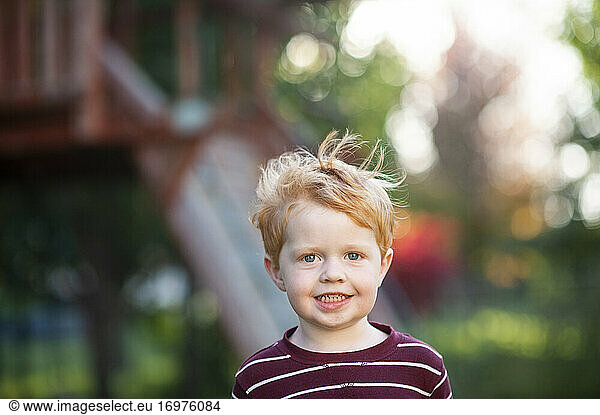 Close up of toddler boy 3-4 years old smiling in backyard during fall