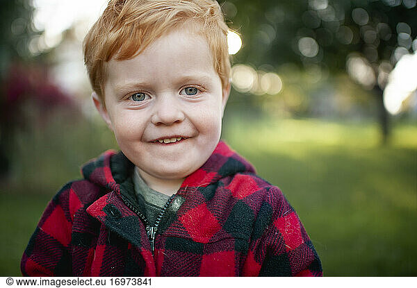 Close up of toddler boy looking and smiling outdoors in winter coat