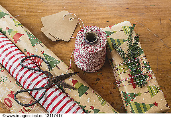 Close-up of twine by scissors and rolled up wrapping papers on table during Christmas