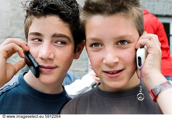 Close_up of two teenage boys talking on mobile phones. Close_up of two teenage boys talking on mobile phones