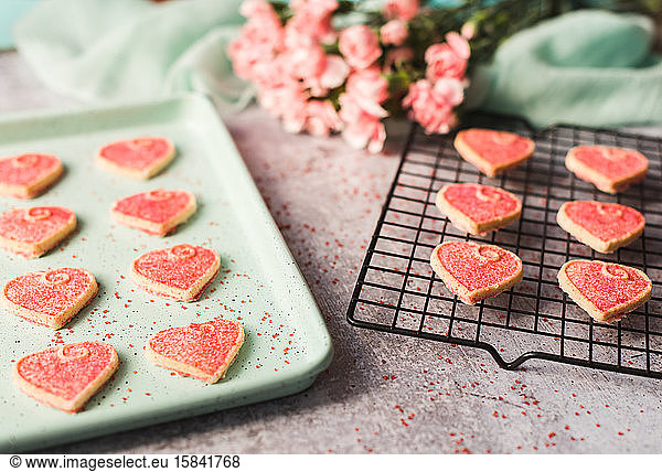 Close up of Valentine's day heart cookies cooling on a pan and rack.