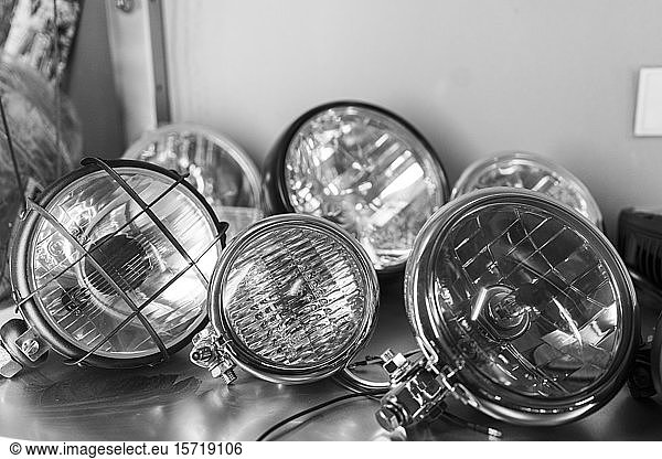 Close-up of various motorcycle headlights lying on shelf