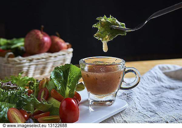 Close-up of vegetables and fruits with dip on table against black background