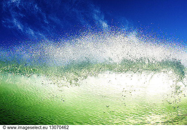 Close-up of wave splashing in sea against blue sky
