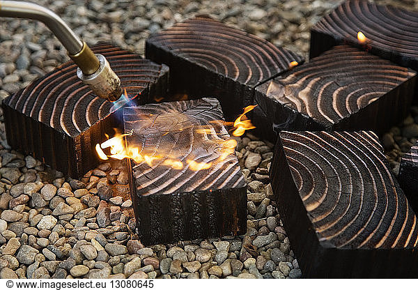 Close-up of welding torch burning wood on stones