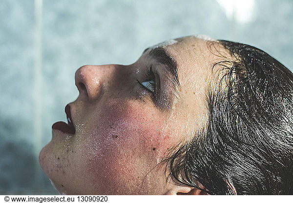 Close-up of wet young woman with make-up looking up while bathing in bathroom at home