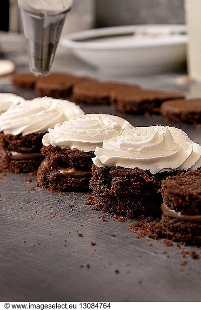 Close-up of whipped cream chocolate sponge cakes at kitchen counter