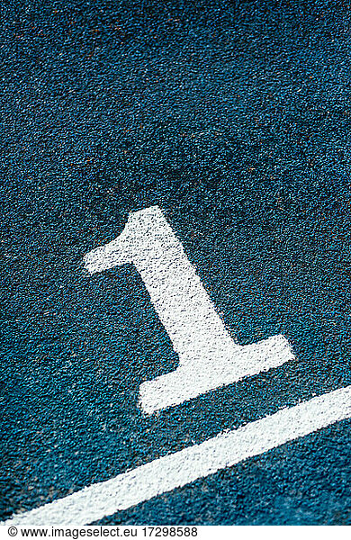 Close-up of white number one on blue running track