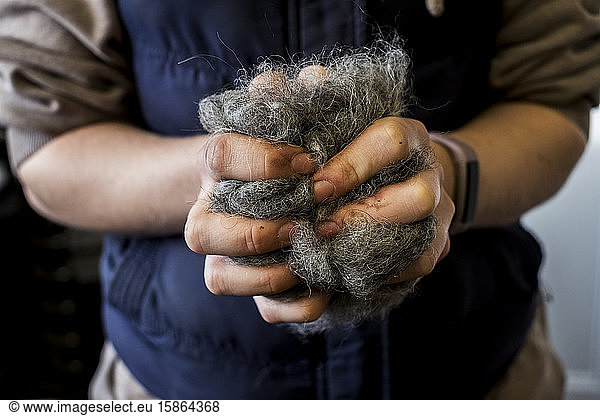 Close up of woman holding bunch of horse hair filling for saddle.