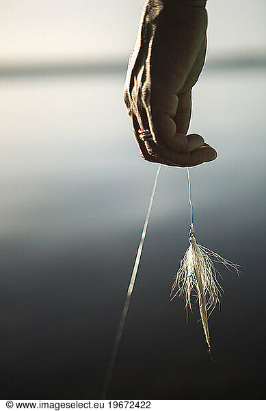 Close-up of woman holding fishing bait on fishing line