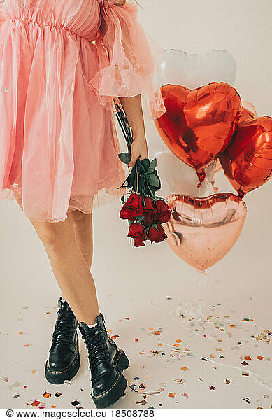 Close up of Woman Holding Red Roses by Heart Balloons and Confetti