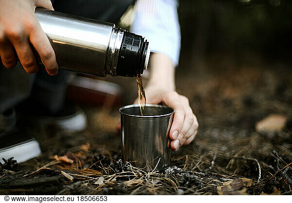 Close-up of woman pouring tea from insulated drink container int