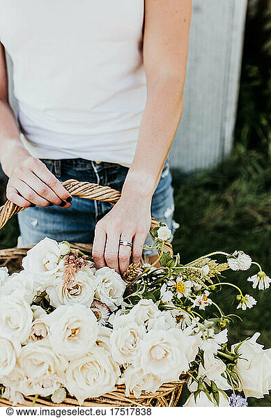 Close up of Woman reaching into basket of fresh picked flowers